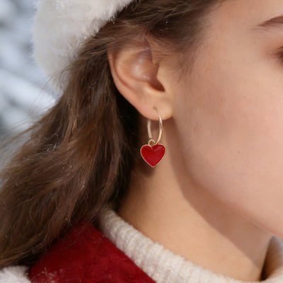 Gold lever-back hoop red enamel heart earring worn on ear outdoors