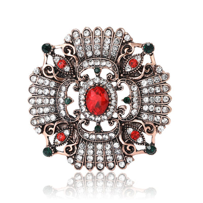 Front view of ornate round medallion centered by a red oval stone