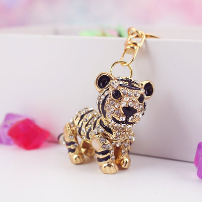 A gold-tone stone-covered tiger keychain stands beside colorful decorative pieces.