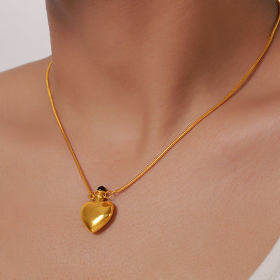 Model wearing gold heart bottle pendant snake chain necklace