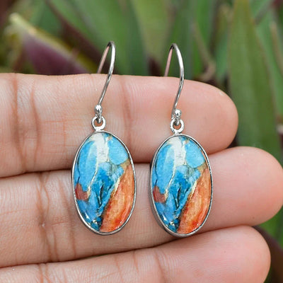 Silver oval blue orange marble drop earrings held in open hand