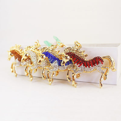 Four gold-tone running horse charms with brown, clear, blue and red rhinestones arranged in a row.