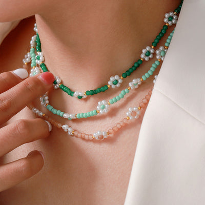 Layered green mint and peach flower bead necklaces on neck