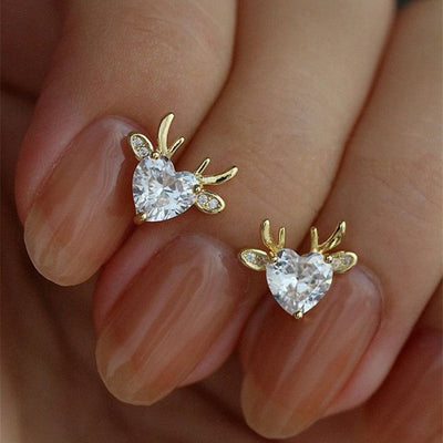 Gold heart antler studs resting on fingertips close-up