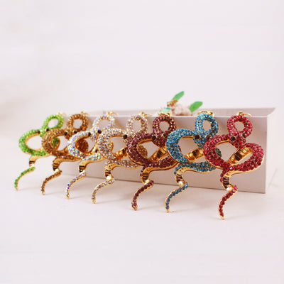 Seven coiled snake pendants displayed in green, gold, iridescent, white, purple, blue, and pink rhinestones.