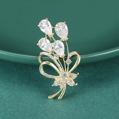 Front view of clear teardrop bouquet brooch with open bow and crystal flower against a white background.