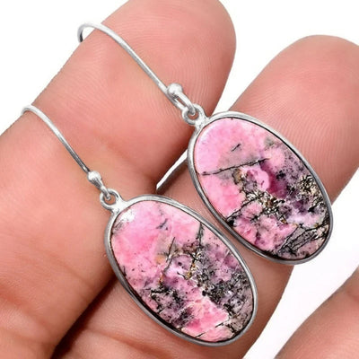 Antique silver pink mottled oval drop earrings held in fingers close-up