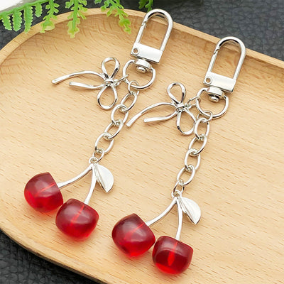 Front display of four bow and cherry enamel clasp keychains with visible colors and attached hardware