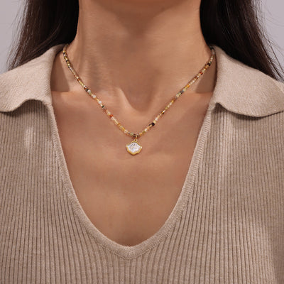 Woman wearing multi-tone natural stone bead necklace with shell pendant
