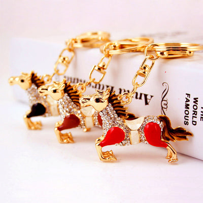 Three gold-tone horse keychains with red, brown, and black color panels arranged together.