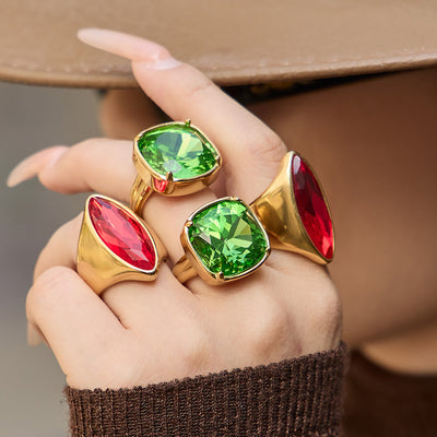 Hand wearing gold marquise red and cushion green stone rings