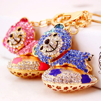Pink and blue rhinestone bear keychains are shown together on a pale background.
