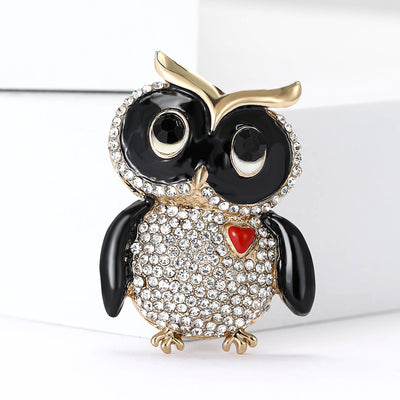 A wide-eyed black owl with a crystal body and small red heart shown on a white background