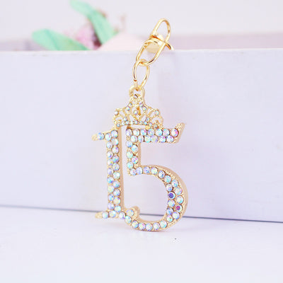 An iridescent rhinestone number 15 charm with a crown and gold-tone attachment.