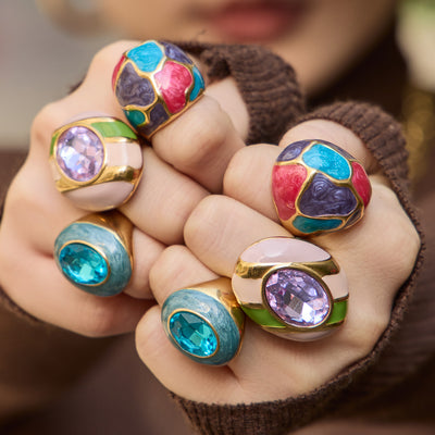 Styled hand view of oversized enamel and glass statement rings in main image 1.