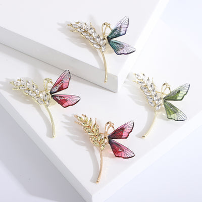 Front product view of the crystal wheat sprig and colorful butterfly brooch on a light background
