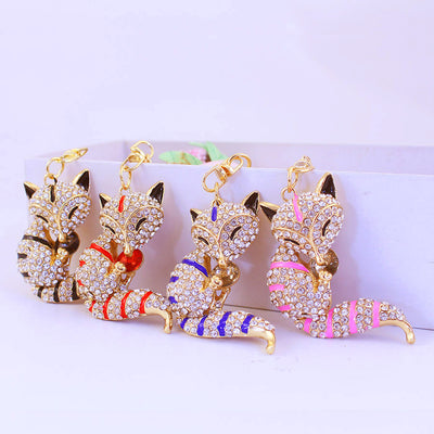 Four rhinestone fox charms with black, red, blue, and pink stripes and small clasps.