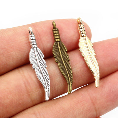 Hand held view of the slender feather charms showing the front shape and finish