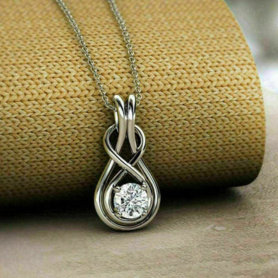 Silver infinity teardrop CZ pendant necklace on woven beige fabric