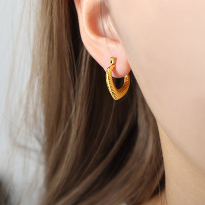 Gold pointed U ribbed hoop earring worn on ear