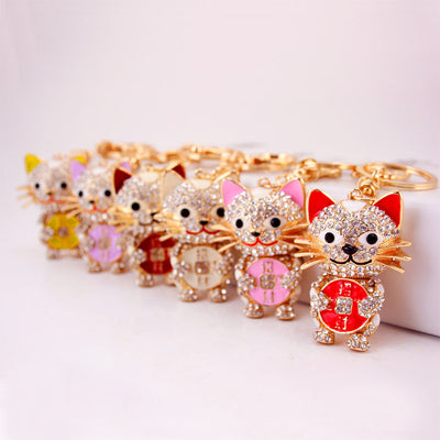 Several lucky cat keychains with different colored ears and coin details arranged in a row.