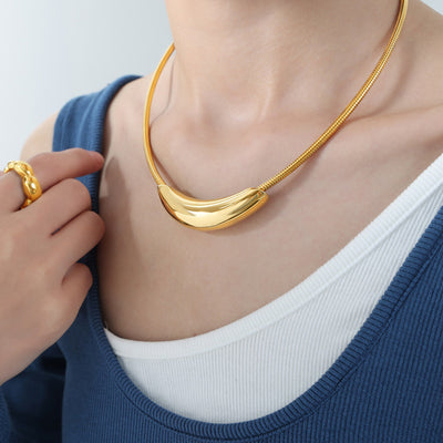 Gold snake chain crescent bar necklace worn at collarbone