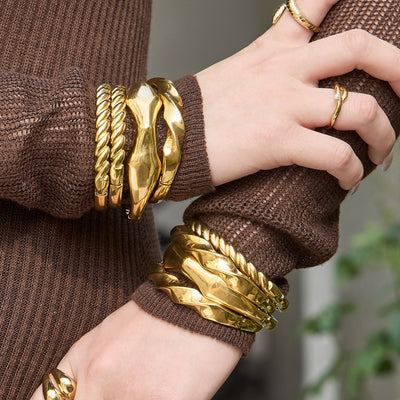 On-wrist view of gold tone sculpted hinged bangles in main image 1.