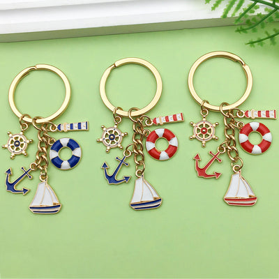 Three gold-tone key rings display blue and red nautical charms on a green background.