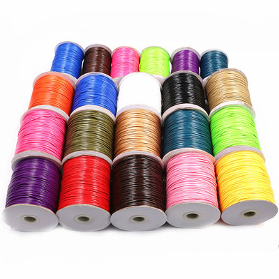 Overview of waxed cord wound on small white spools in a broad assortment of vivid and neutral colors arranged on a light