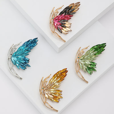Front view of the crystal wing brooch showing a sweeping feather-like crystal wing in a curved metal setting