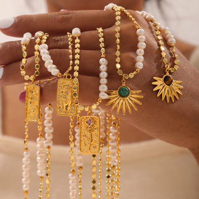 Hand holding assorted gold pearl disc necklaces with plate and sun pendants