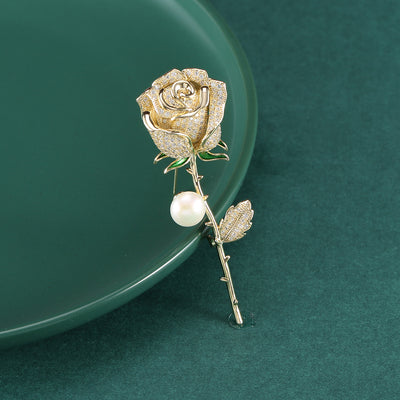 Gold pavé crystal rose stem brooch with pearl on green plate