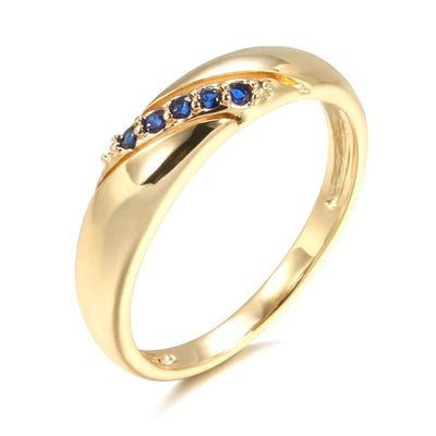 Gold crossover band ring with blue stones on white background