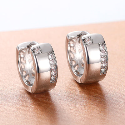 Silver U-shape wide huggie hoops with CZ accents on copper surface