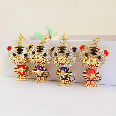 Four gold-tone tiger charms with rhinestone-covered heads and different body colors.