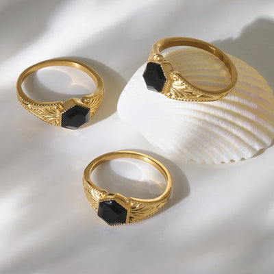Styled hand view of black natural stone hexagonal rings in main image 1.