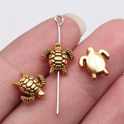 Antique Silver, Antique Gold dimensional sea turtle small-hole bead front view on fingertips