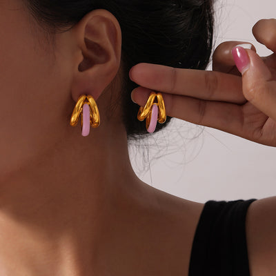 Gold double C pink enamel hoop studs worn and held by model