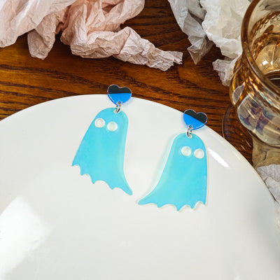 Iridescent blue ghost earrings with heart posts on white plate