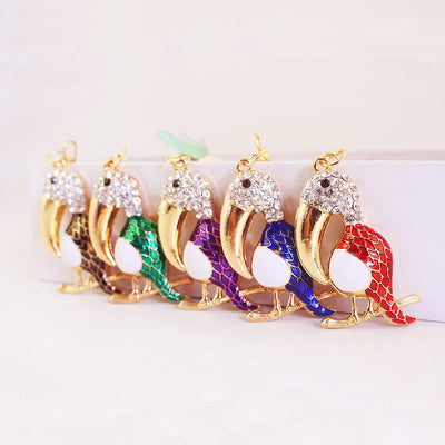 Five gold-tone toucan charms displayed in black, green, purple, blue, and red.