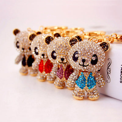 Several stone-covered panda keychains displayed together with different colored vests.