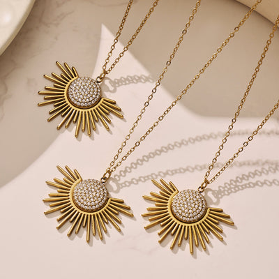 Three gold sunburst pavé pendant necklaces on beige surface