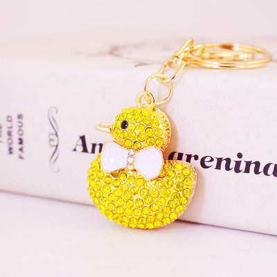 Close-up of a yellow rhinestone duck charm attached to a gold-tone key ring
