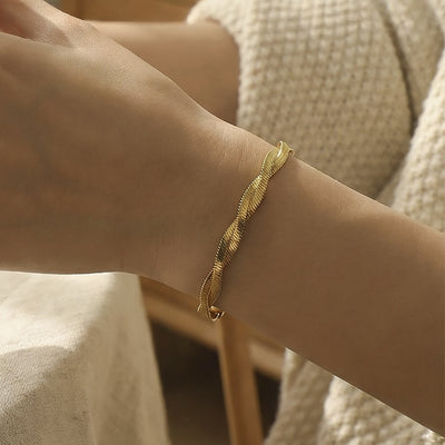 Gold twisted herringbone bracelet worn on wrist indoor light
