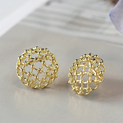 Gold openwork lattice dome stud earrings pair on grey surface