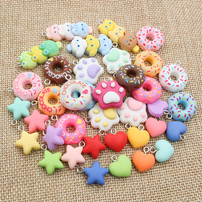 Assorted colorful resin star, heart, donut, and treat charms arranged together on a plain background