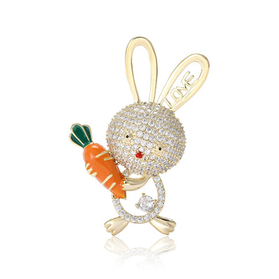 Front view of crystal rabbit brooch holding an orange enamel carrot against a white background.