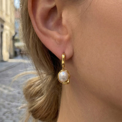 Side profile of model wearing gold irregular C-stud with white pearl drop earring
