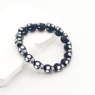 Black plastic skull stretch bracelet on white stone side angle
