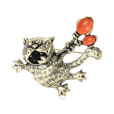 Front view of the cat with orange balloon brooch in two metal tones with polished metal detail on a white background